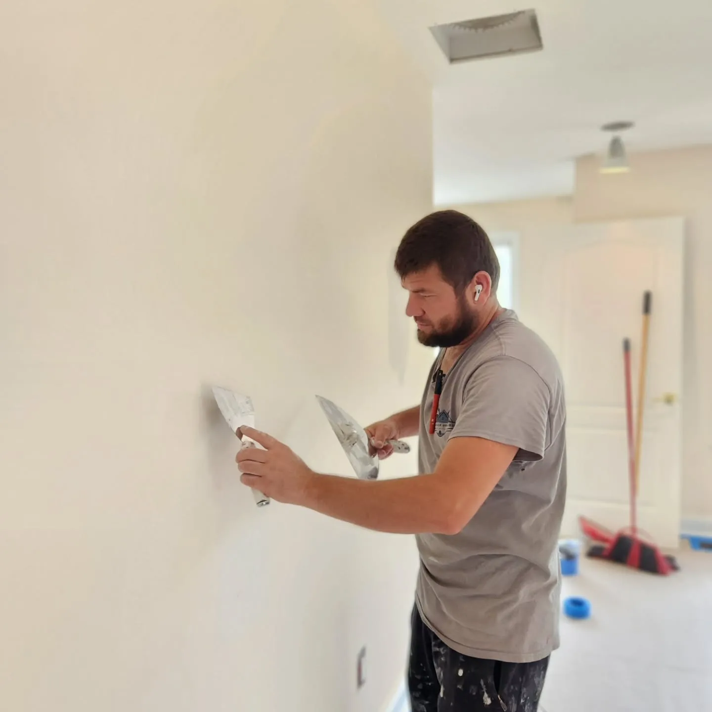 Professional wall finishing by Dream Space Remodeling featuring an expert craftsman applying joint compound for a smooth, paint-ready surface.