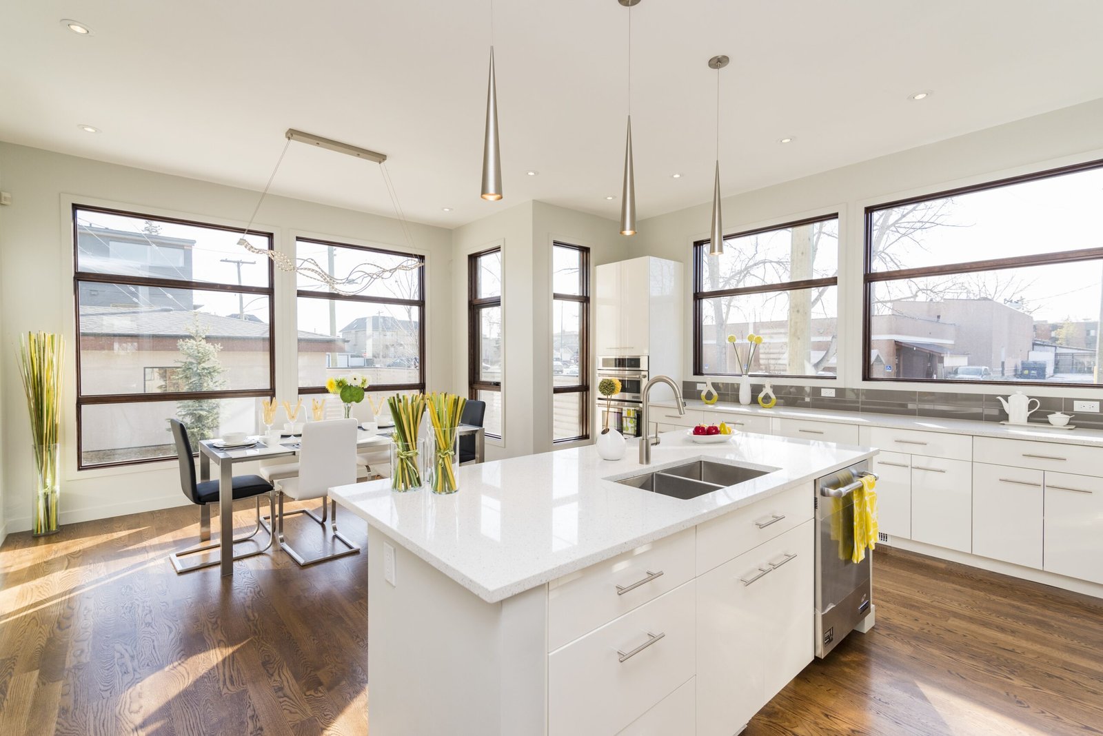 Dream Space Remodeling - Stunning open-concept kitchen and dining area renovation featuring large windows for natural light, white cabinetry, a central quartz island, and modern hardwood flooring.